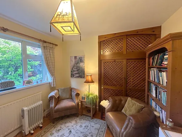 Helen's counselling room: two leather armchairs, a lamp, bookshelves and a window onto the garden